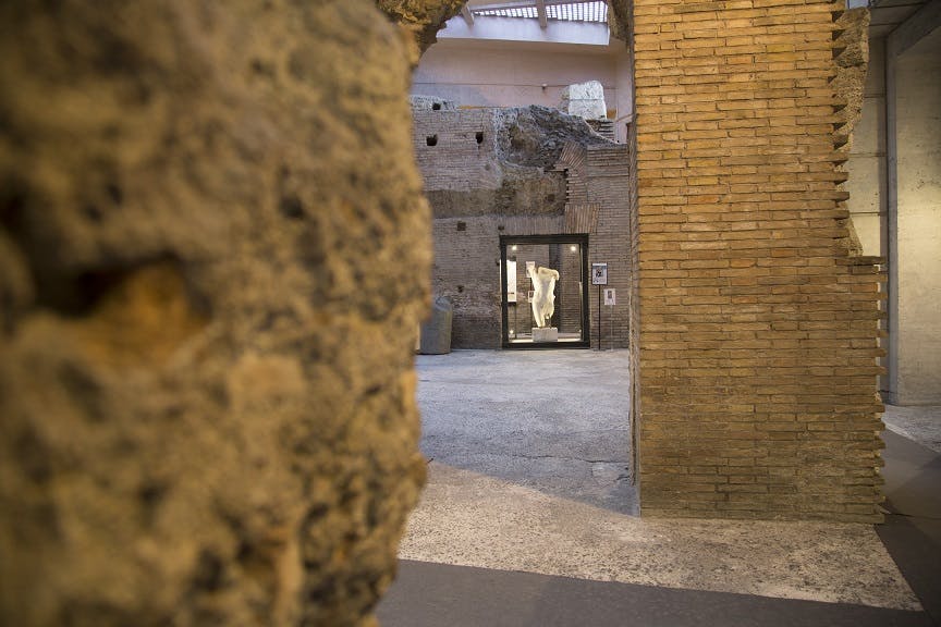 透过庭院内的玻璃箱，欣赏白色雕像的古老砖块遗迹。