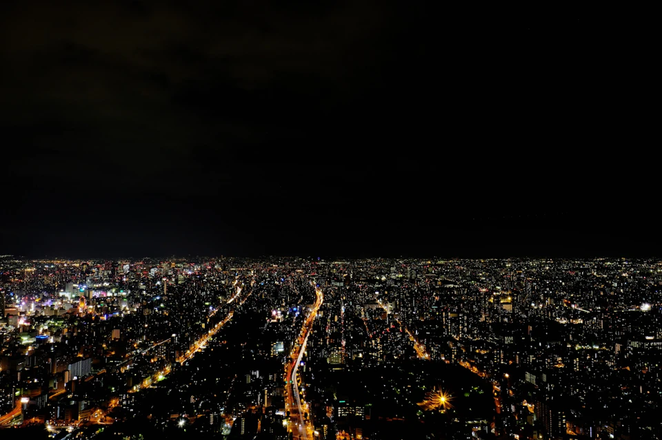 Aerial view of a cityscape at night, showing illuminated streets and buildings under a dark sky.