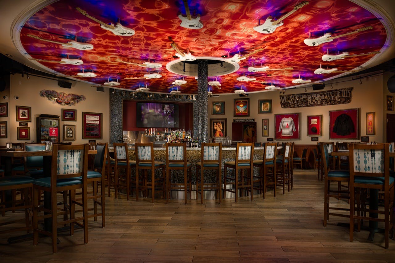 酒吧设有圆形柜台、众多凳子、色彩缤纷的吉他主题天花板，墙上挂着摇滚纪念品。