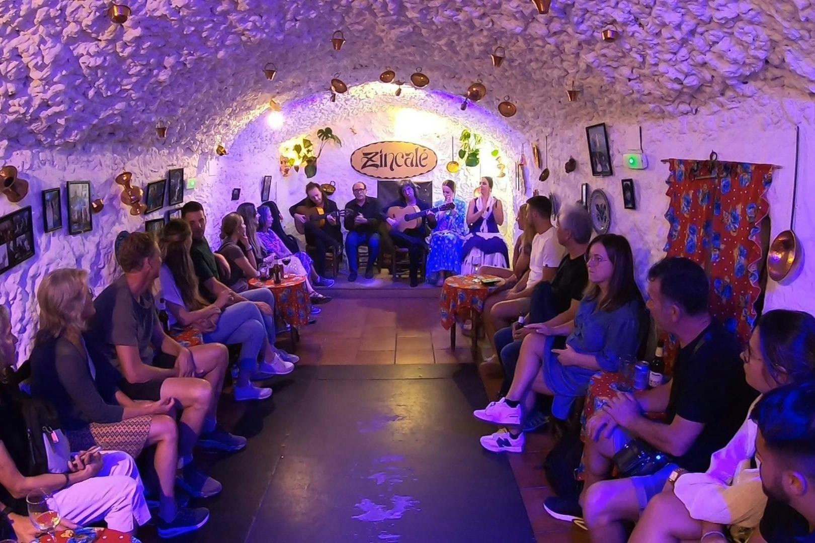 Eine Gruppe von Menschen, die eine Live-Musikvorstellung in einem dekorierten, höhlenartigen Raum mit stimmungsvoller Beleuchtung und in Reihen angeordneten Stühlen verfolgen.