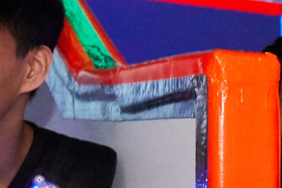 Two individuals holding laser tag guns in an indoor arena with colorful barriers and futuristic lighting.