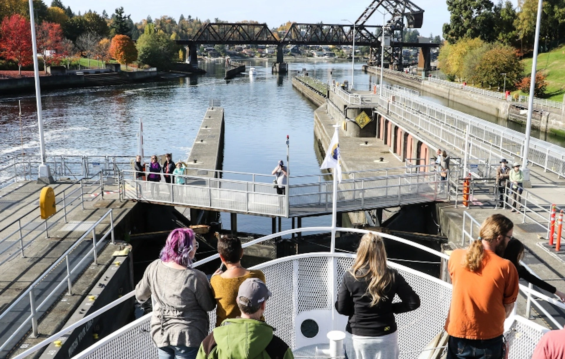 People on the bow of an Argosy boat look out over the lock chamber gates to the salt water beyond