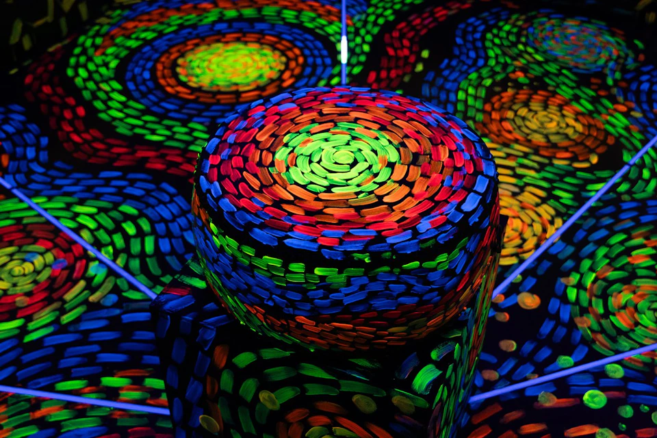 A colorful, abstract pattern of swirling neon hues in a circular arrangement, resembling an artistic light display.