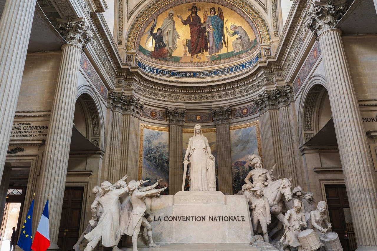 玛丽安雕像位于基座上，基座上刻有“La Convention Nationale”字样，周围环绕着人物，上面还有一幅详细的壁画。