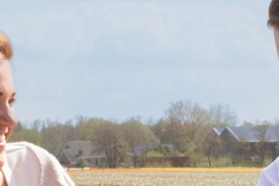 Two people standing in a colorful tulip field next to a sign saying "Welcome to Tulip Heaven."