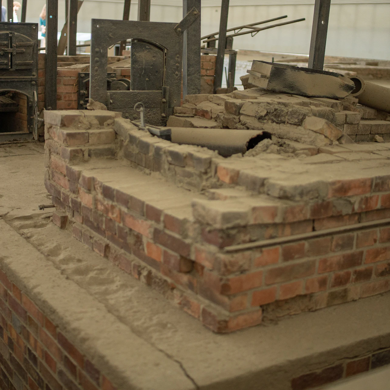A damaged brick structure with metal equipment, appearing as a historical industrial site or furnace remains.