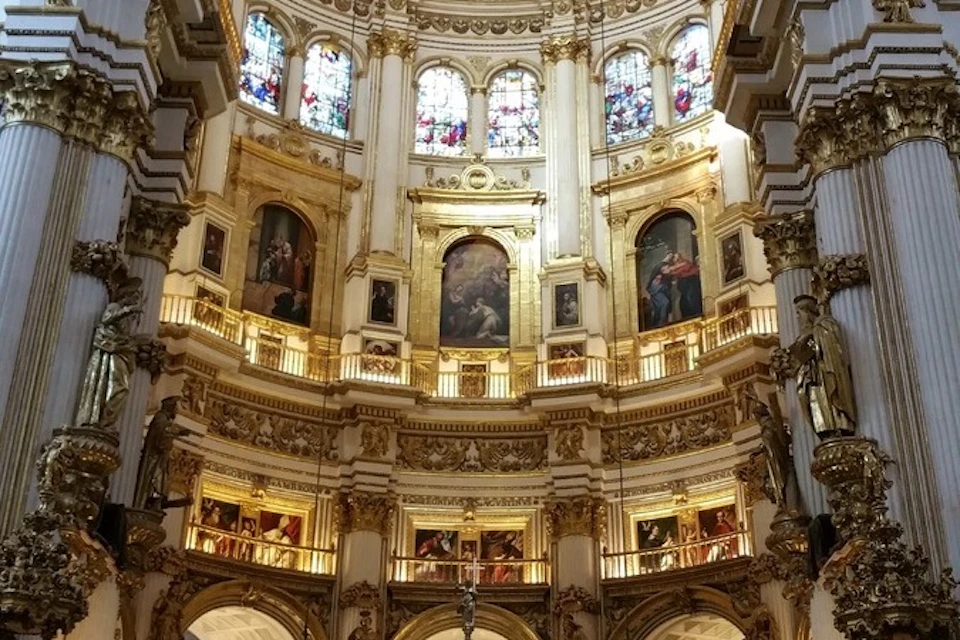 Ornate interior of a cathedral featuring gold accents, arched windows, and religious artwork on the walls.