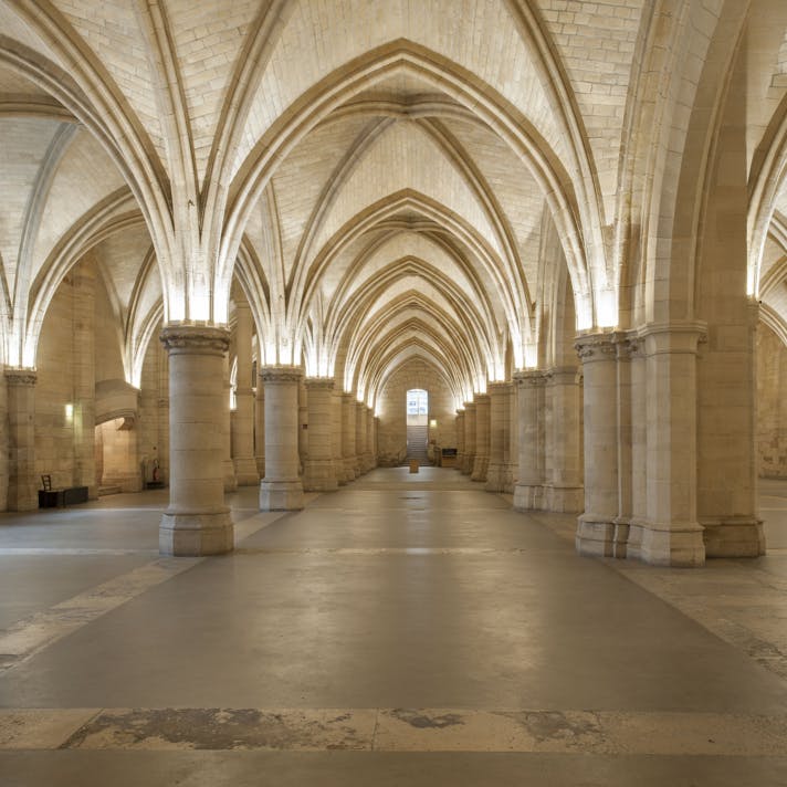 一座空荡荡的大厅，拱形天花板、带灯光的拱门和石柱。