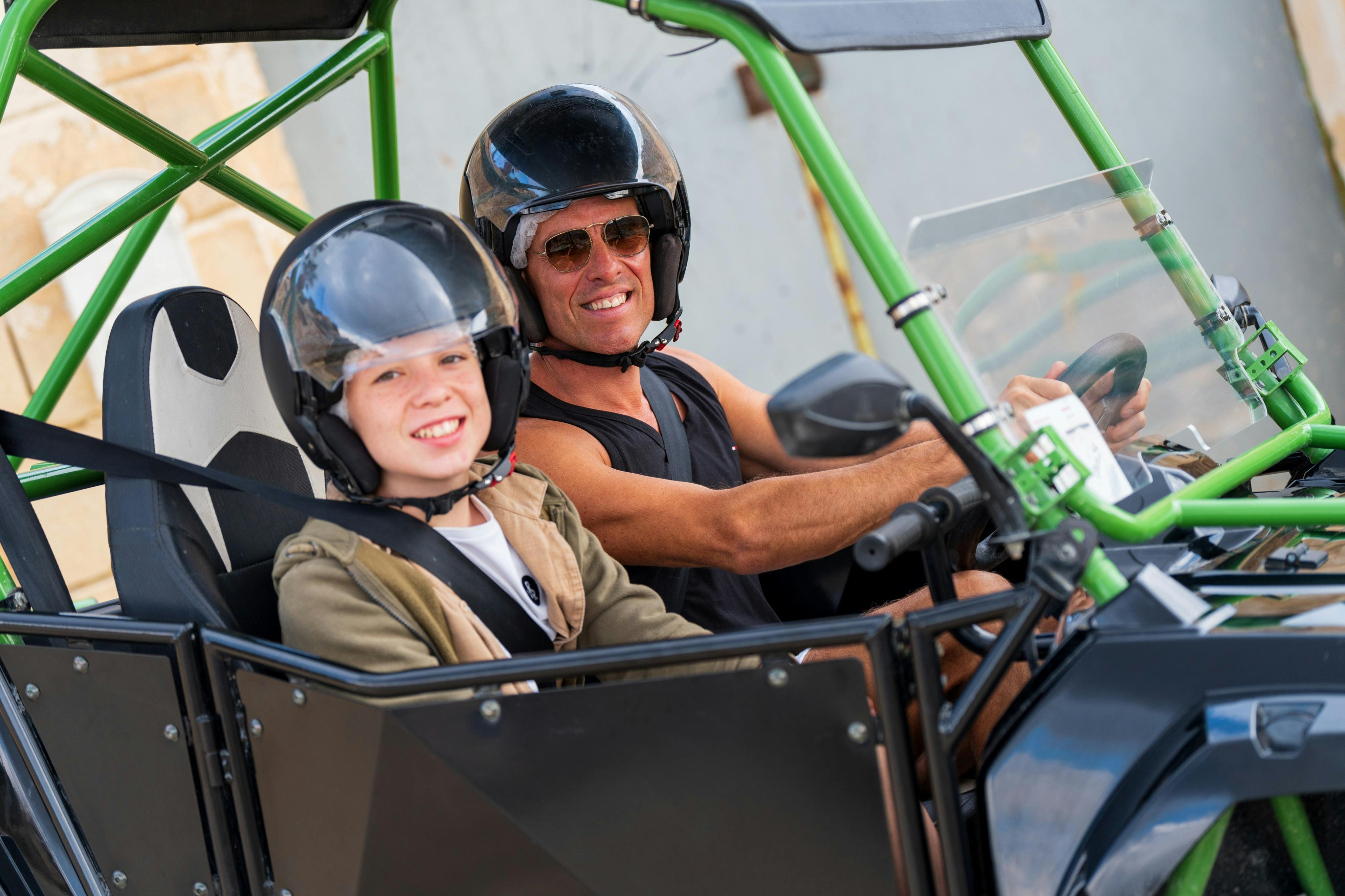 Due persone che indossano il casco sedute in un fuoristrada, sorridono e si godono il momento.