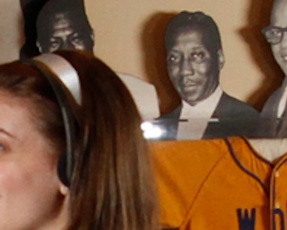 Two women smiling inside a music museum with historic photos, memorabilia, and old microphones displayed.