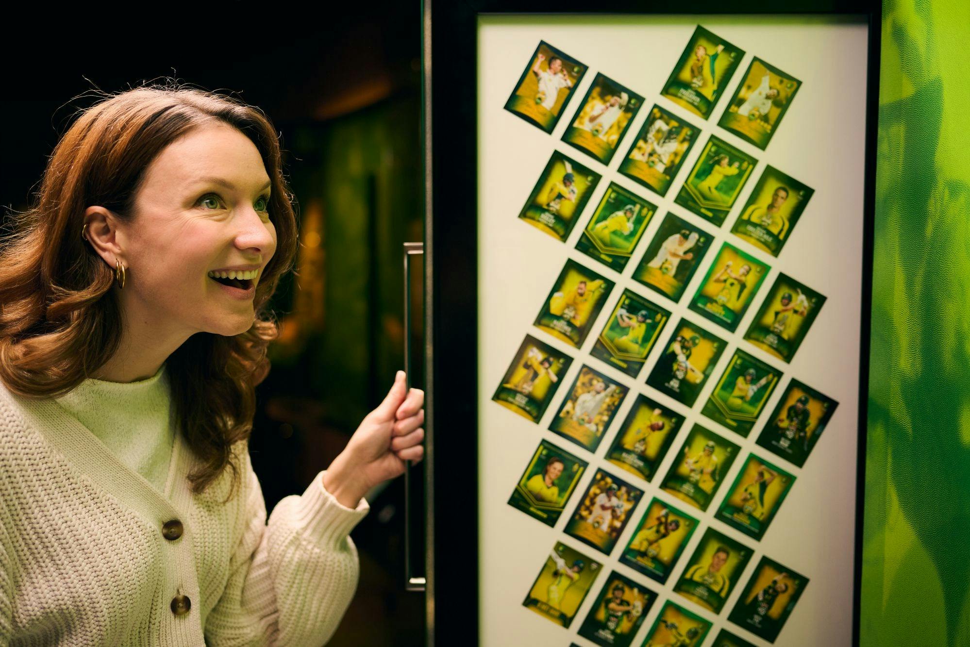 Une femme souriante ouvre une porte à l'intérieur de laquelle se trouve une grille de photos colorées.