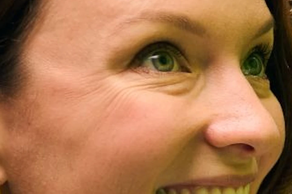 A smiling woman is opening a door with a grid of colorful photos displayed on the inside.