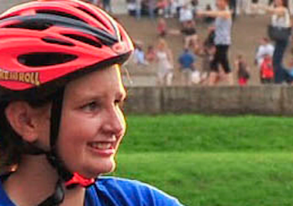 Two cyclists wearing helmets in front of the Lincoln Memorial, with one pointing and a crowd gathered on the steps in the background.