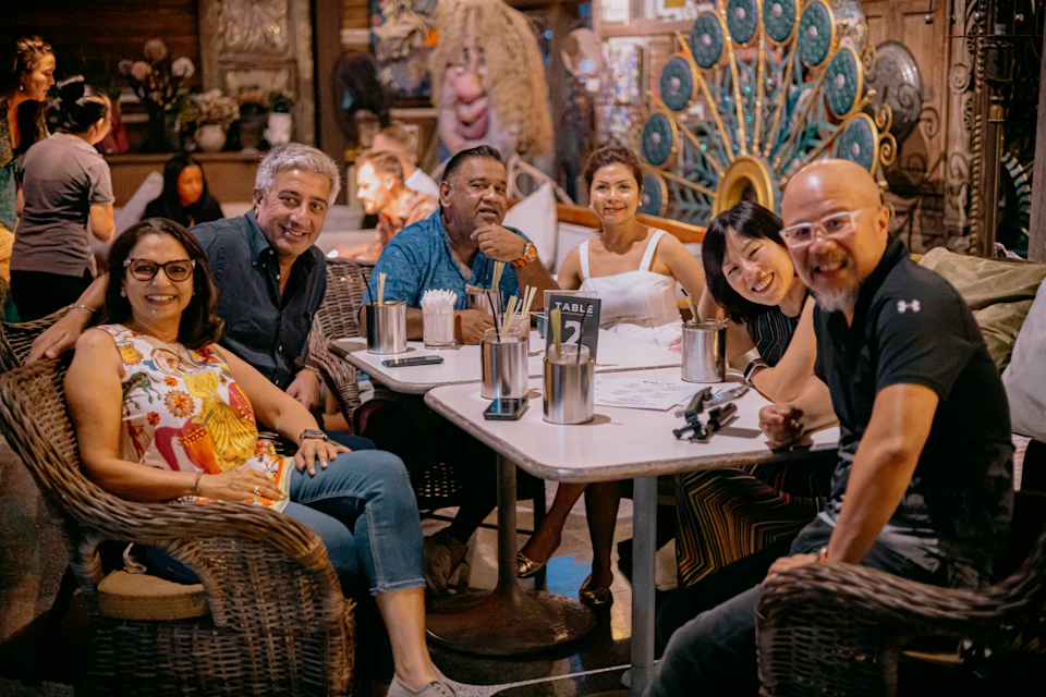 A group of five people are sitting around a table in a lively, colorful restaurant.