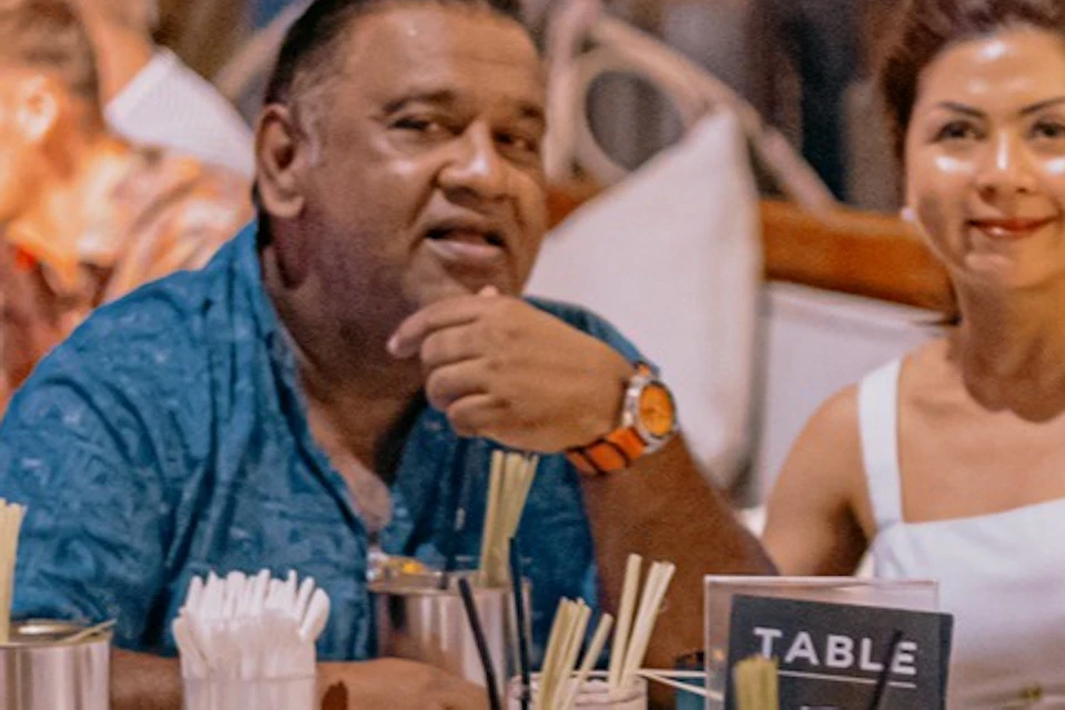 A group of five people are sitting around a table in a lively, colorful restaurant.