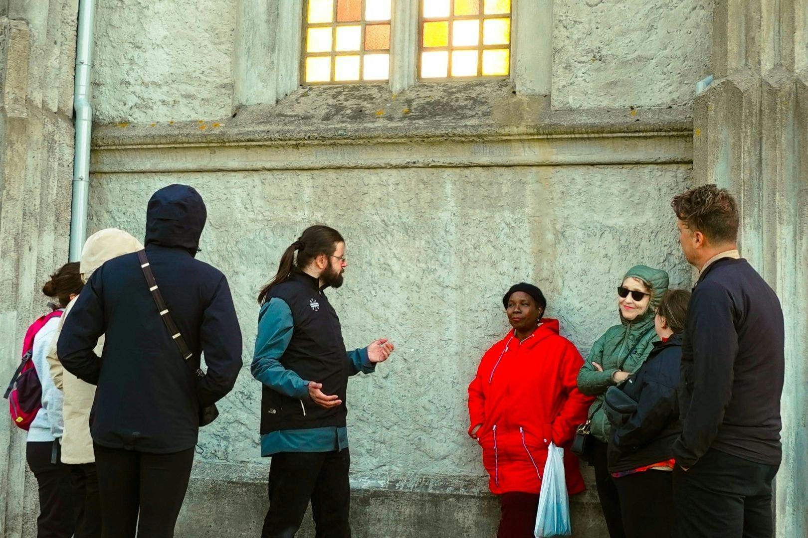 질감이 살아있는 돌과 형형색색의 유리창이 있는 외벽 옆에 5명이 모여 대화를 나누고 있습니다.