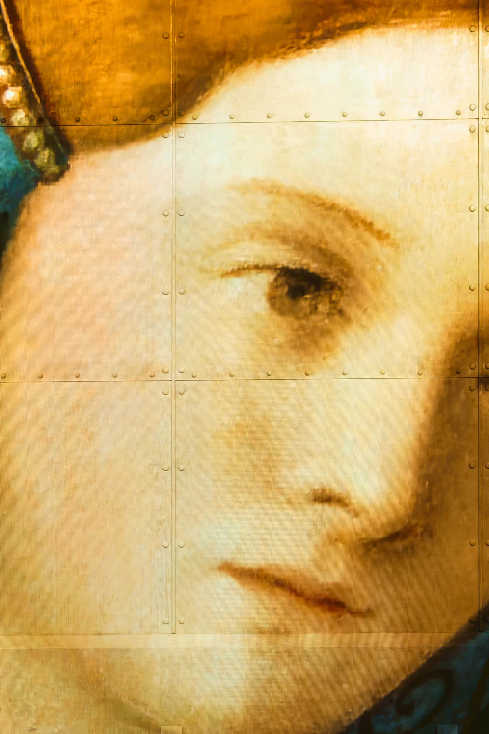 A large mural of a classical-style portrait of a woman with a blue and green patterned headdress, with two people silhouetted below.
