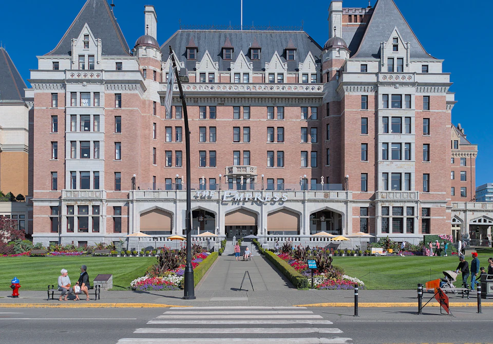 Front view of a large, historic brick hotel named "The Empress" with manicured gardens and a pedestrian walkway leading to the entrance.