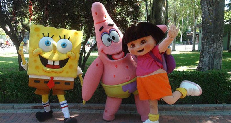 两个穿着帕特里克·斯塔（ Patrick Star ）和探险家多拉（ Dora ）服装的人在公园里摆姿势，周围环绕着树木和绿