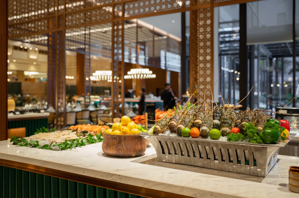 An elegant buffet setup featuring fresh seafood, fruits, and vegetables with a decorative background in a restaurant.