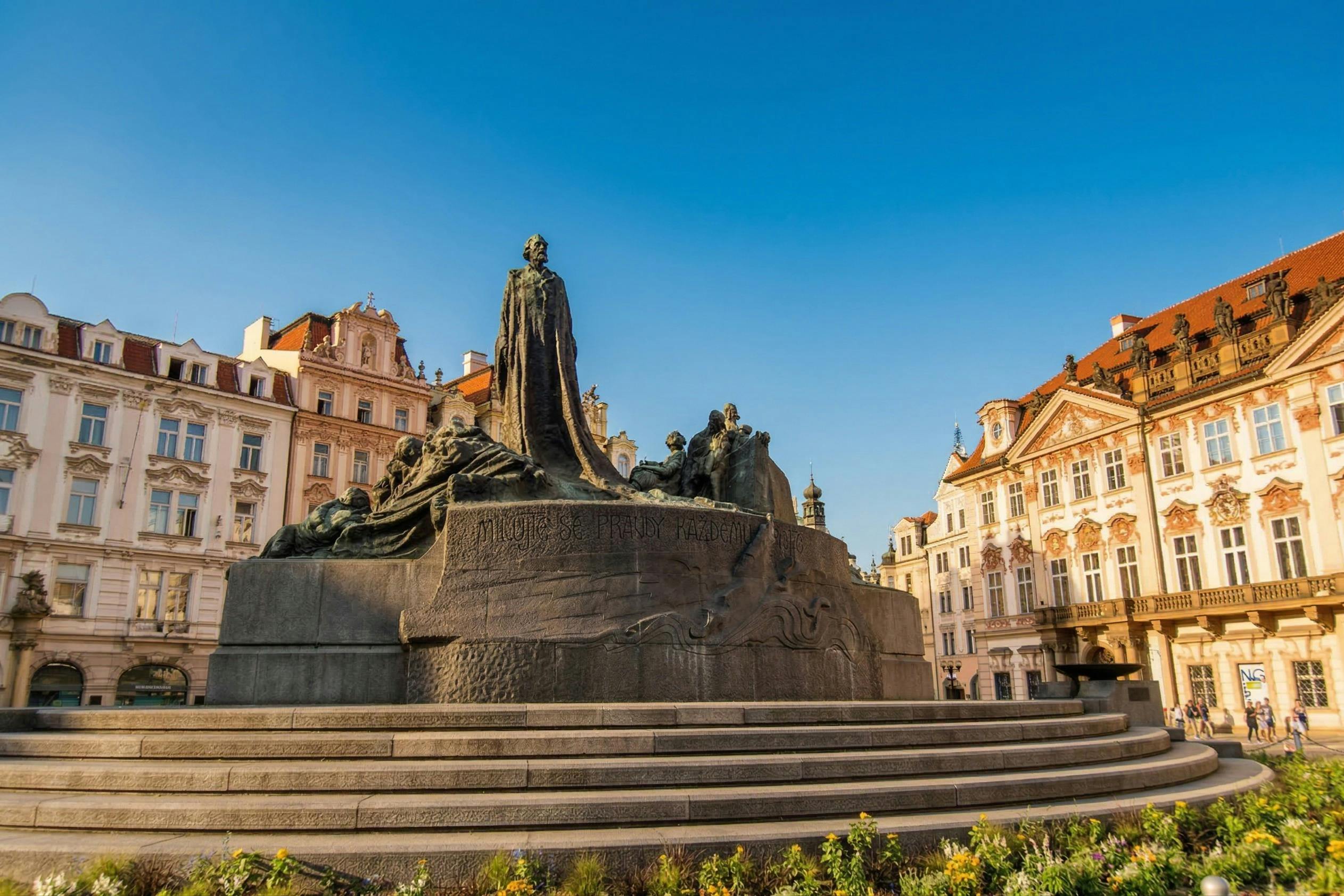맑고 푸른 하늘 아래 화려한 건물로 둘러싸인 마을 광장의 역사적인 동상입니다.