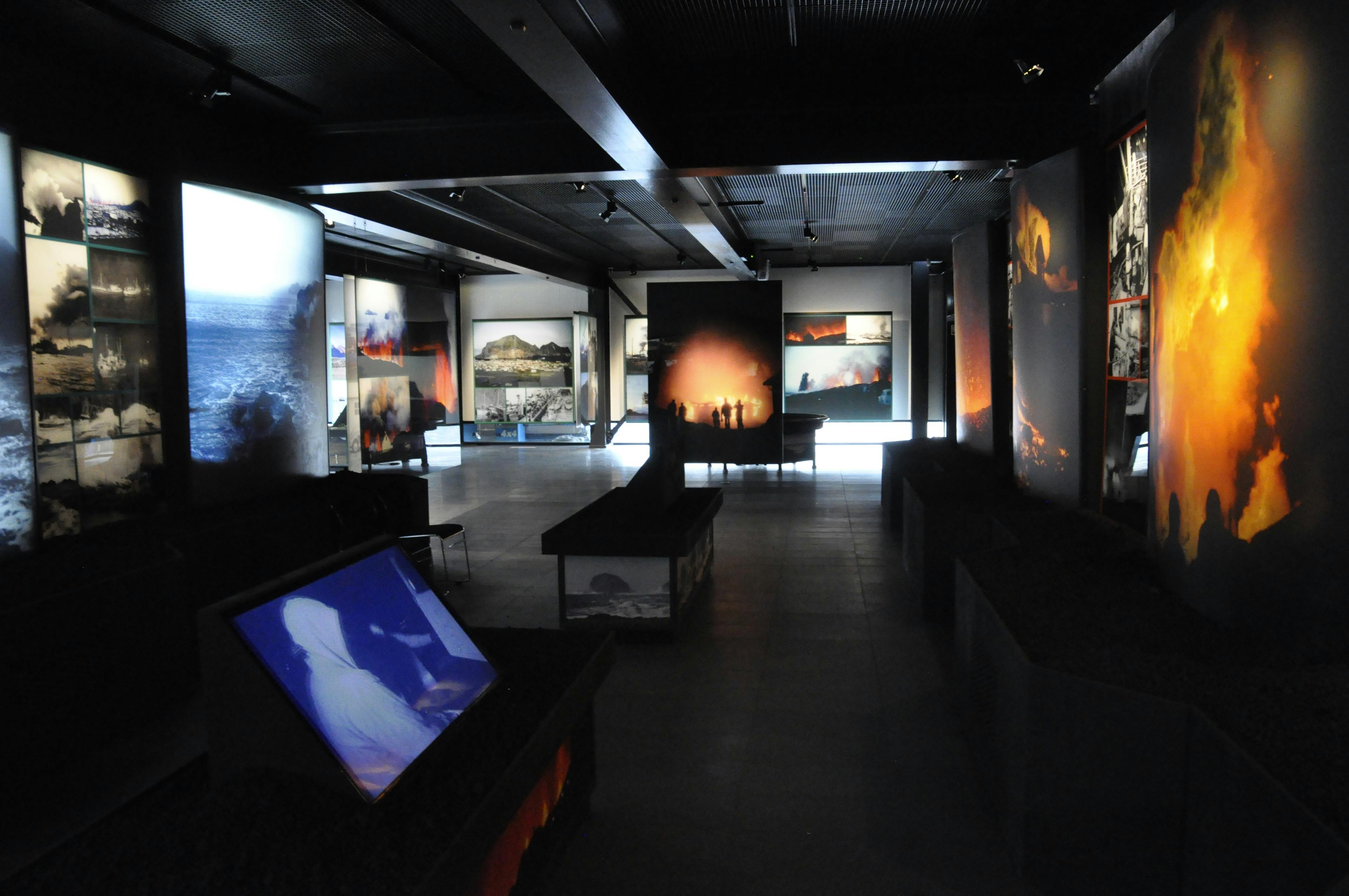 A modern gallery with backlit photographs and digital screens displaying various scenes, including landscapes and silhouettes.