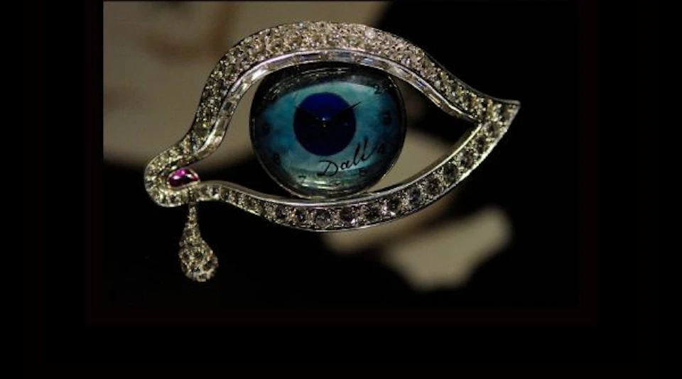 A jeweled eye-shaped watch with diamond-studded borders and a teardrop, featuring a blue eye design on the watch face.
