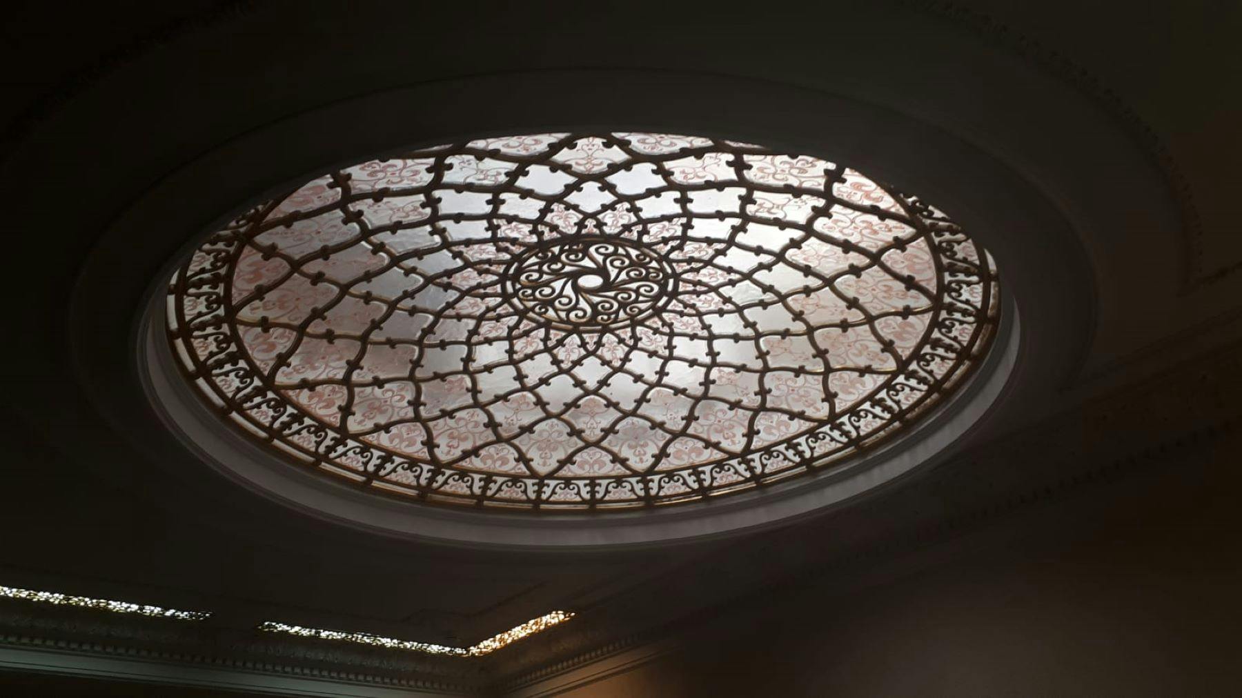 Un intrincat sostre de vitralls de forma ovalada amb patrons geomètrics simètrics i delicats dissenys florals.