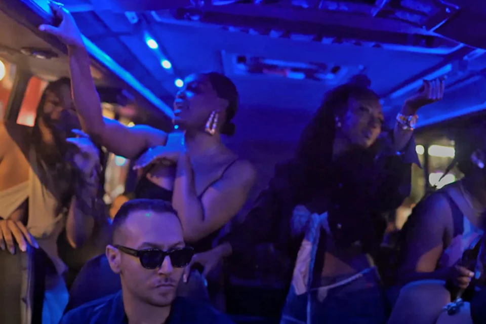 People dance and enjoy themselves under blue lighting in a dimly lit party environment.