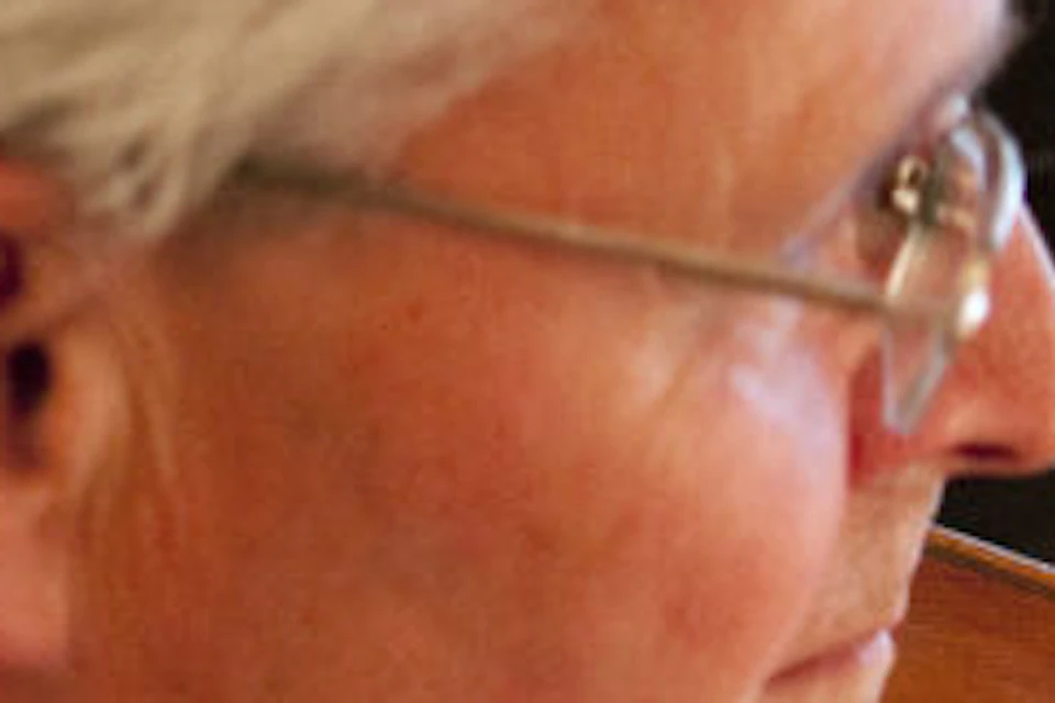 Elderly man in formal attire playing a violin with a bow, focused expression, soft lighting highlights the instrument.