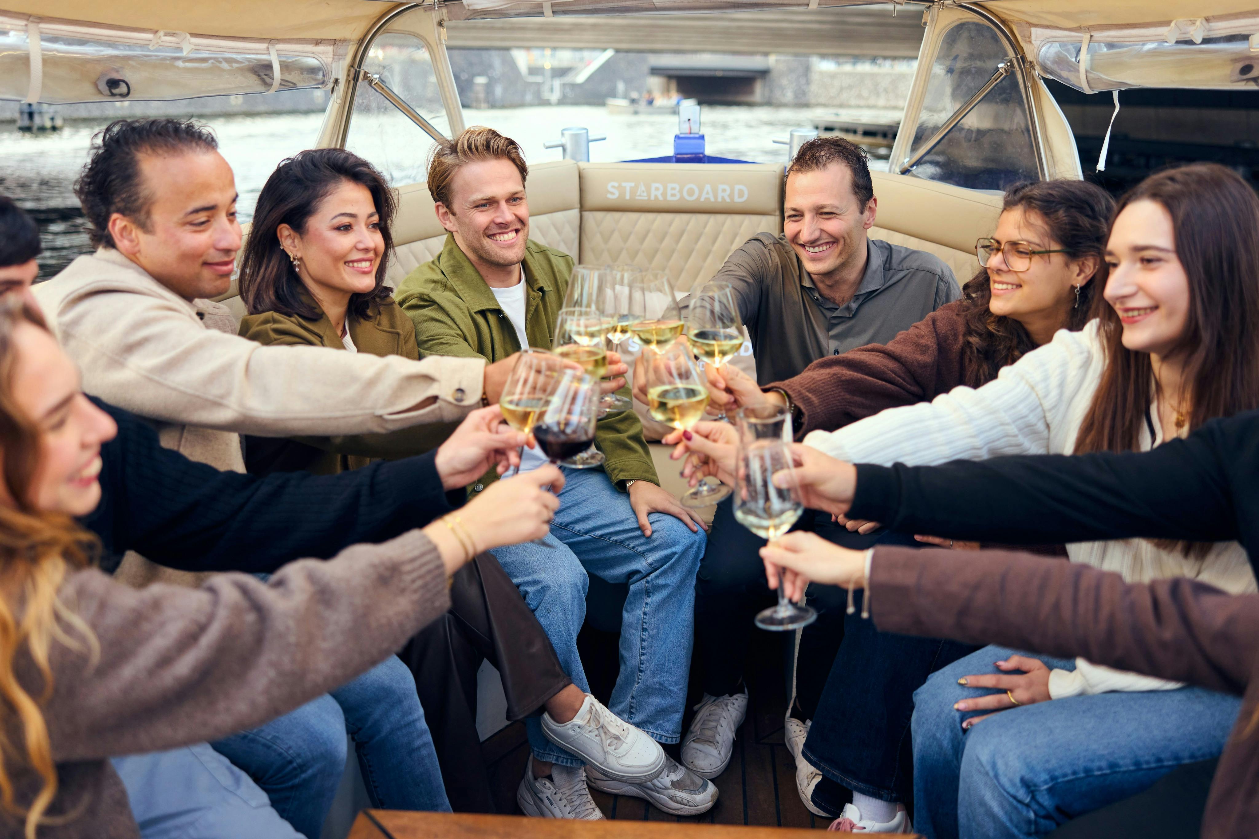 Um grupo de pessoas sentadas num barco, a beber copos num brinde de celebração, a sorrir e a desfrutar do momento.