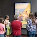 Gids en groep kijken naar een werk van Seurat