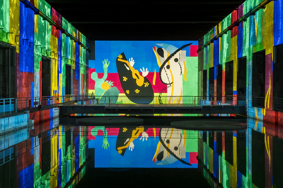 A vibrant mural with abstract figures, colorful shapes, and reflections on water in a gallery space.