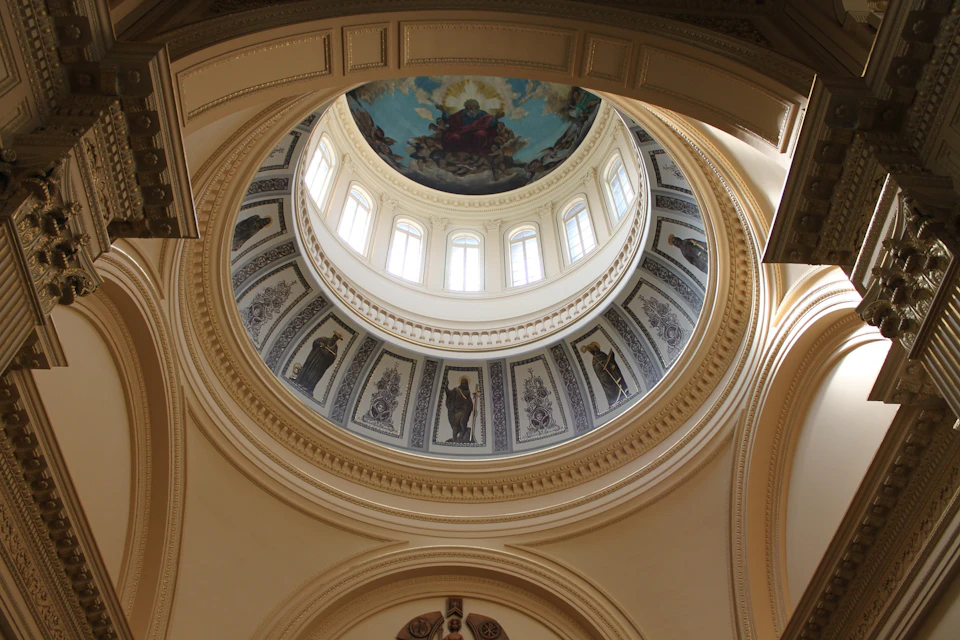 Ornate dome interior with detailed frescoes, surrounded by small arched windows. Central fresco depicts a heavenly scene.