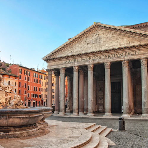 Historisk stenbyggnad med stora pelare och en triangulär prydnad, i anslutning till en stenfontän med skulpterade figurer.