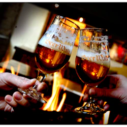 Två händer klirrande ölglas med "Beer Walk" -logotyper, med en eld i bakgrunden.