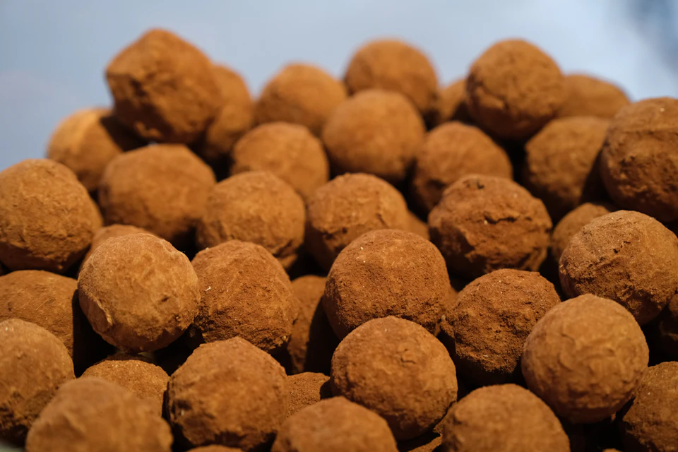 A pile of cocoa-dusted chocolate truffles against a light background.