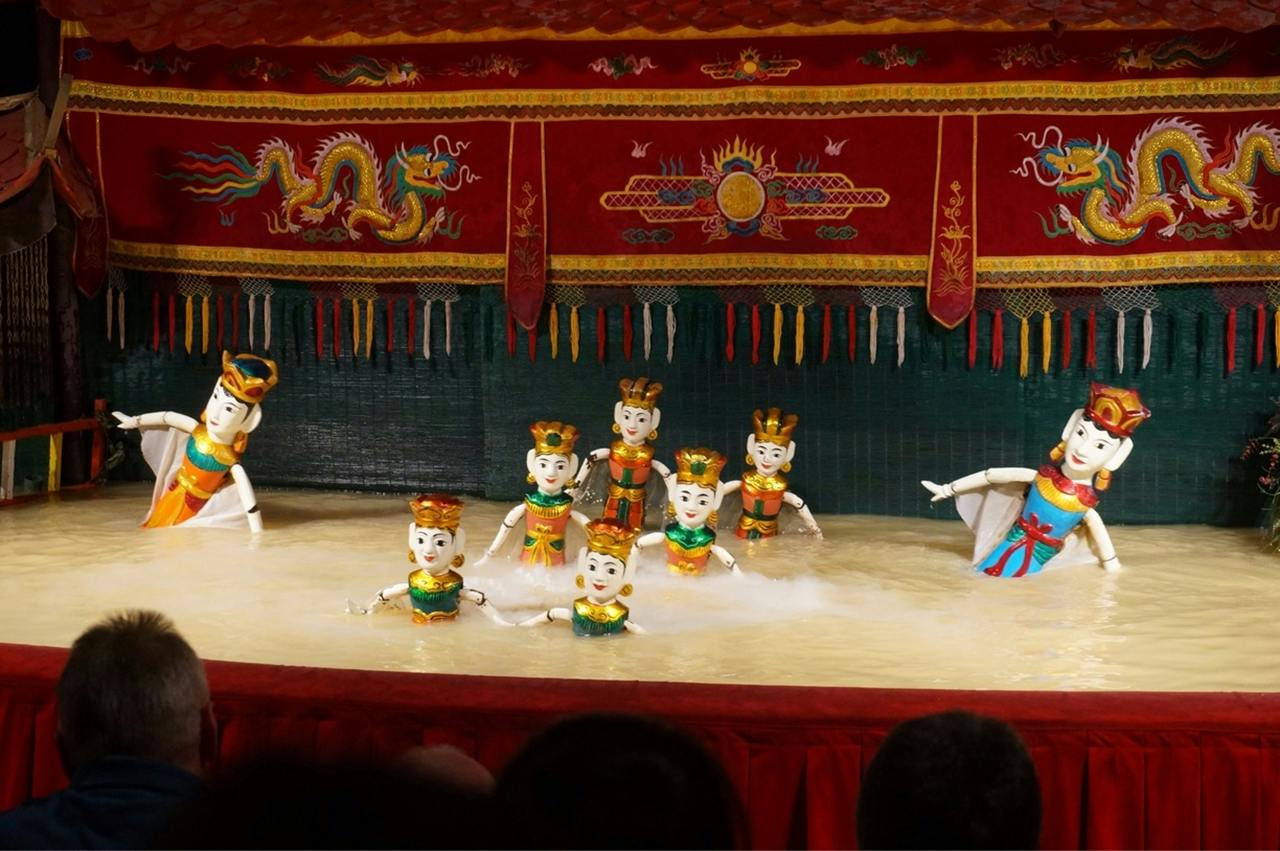 Water puppets performing on a water stage, with colorful traditional designs and decorations in the background.