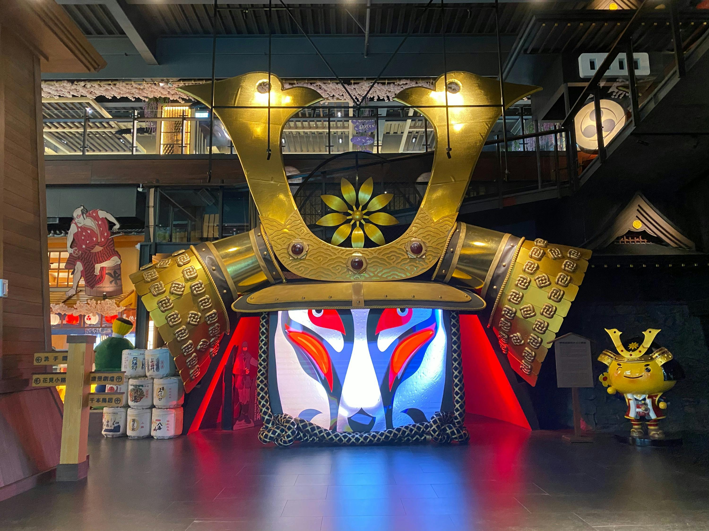 Large decorative display with a golden helmet motif and a colorful illuminated face design in a modern indoor setting.