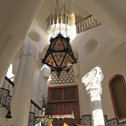 En hängande dekorativ lykta i en utsmyckad interiör med kolumner, bågar, en trädörr och kakelutsmyckade väggar.