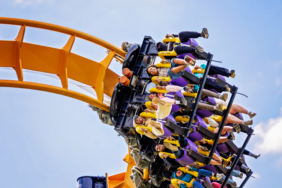People on a roller coaster at Six Flags, with hands up in excitement, descending a track with blue sides.