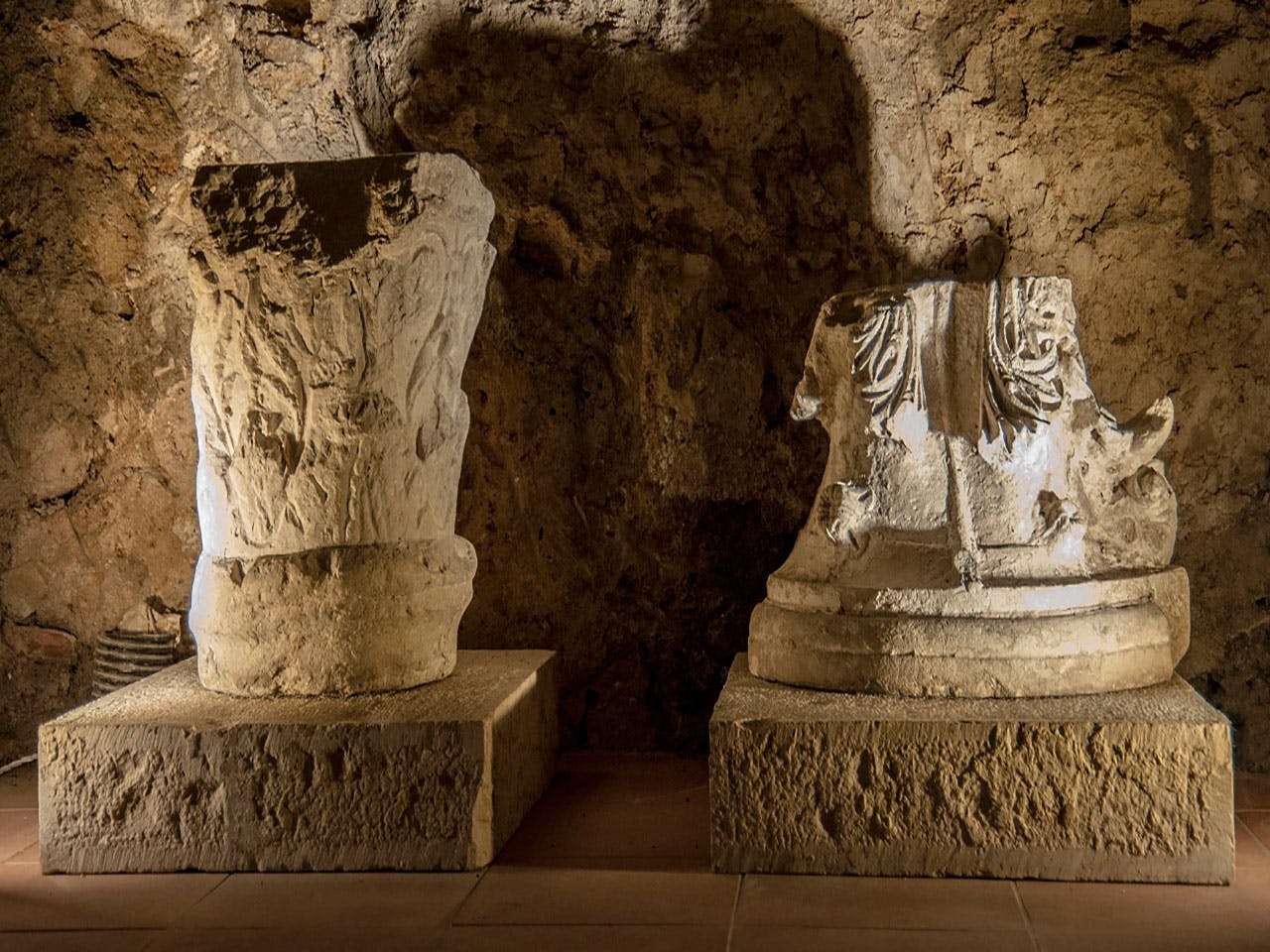 两座古老的石雕雕像在昏暗的岩石洞穴环境中展出。