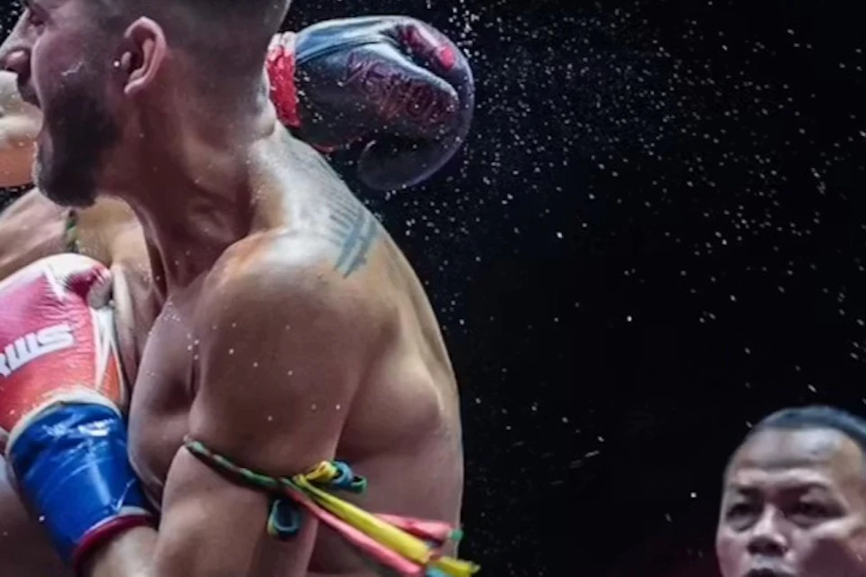 Two fighters compete in a Muay Thai match in a boxing ring, with a referee observing.
