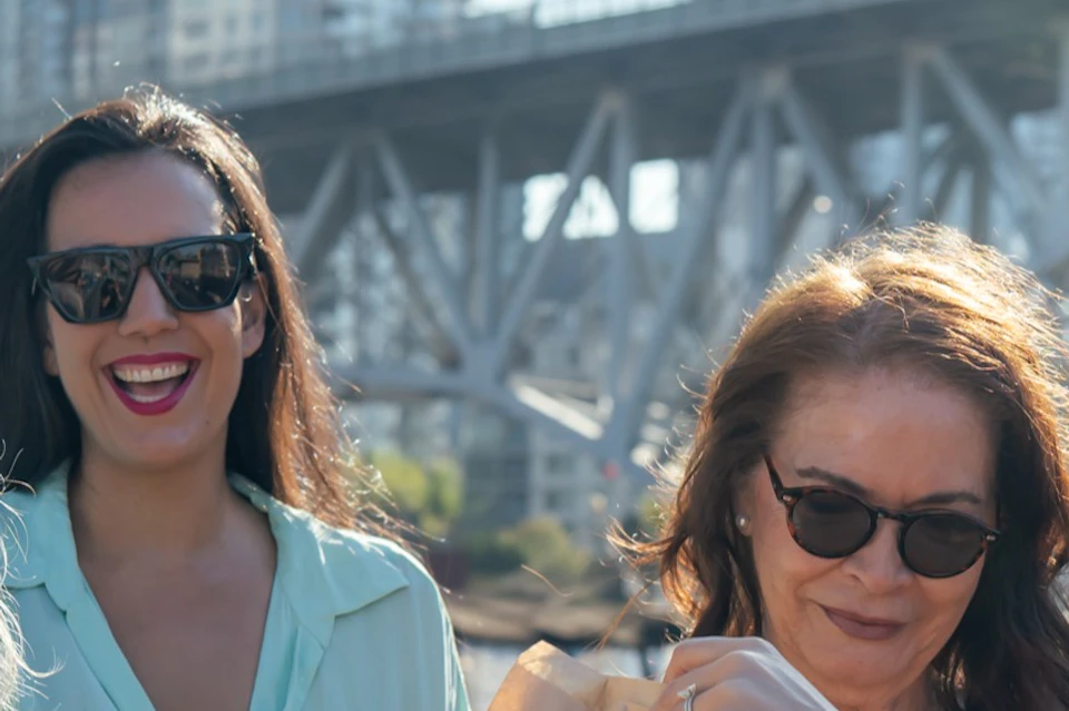 Five people smiling and holding Terra Breads bags by a waterfront railing, with a bridge and city buildings in the background.