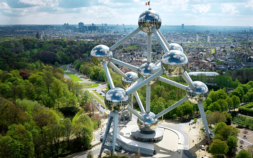 Aerial view of the Atomium structure in Brussels, with its metallic spheres and connecting tubes, surrounded by a park and cityscape.