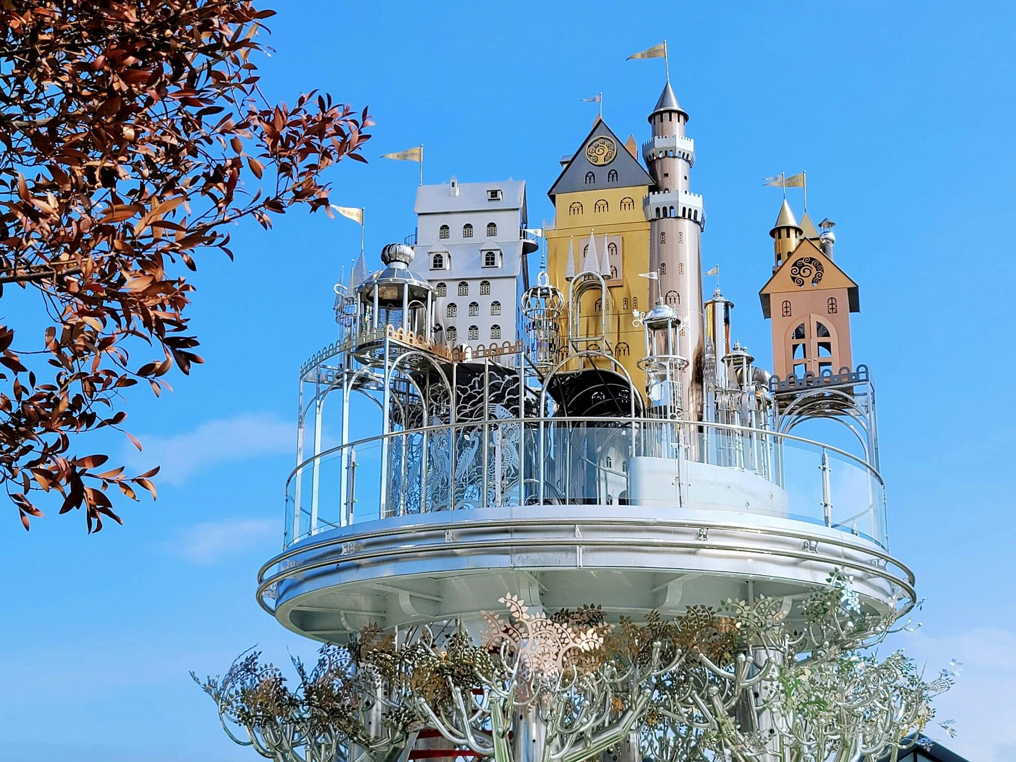 A whimsical structure resembling a collection of small, colorful castle-like buildings against a blue sky.