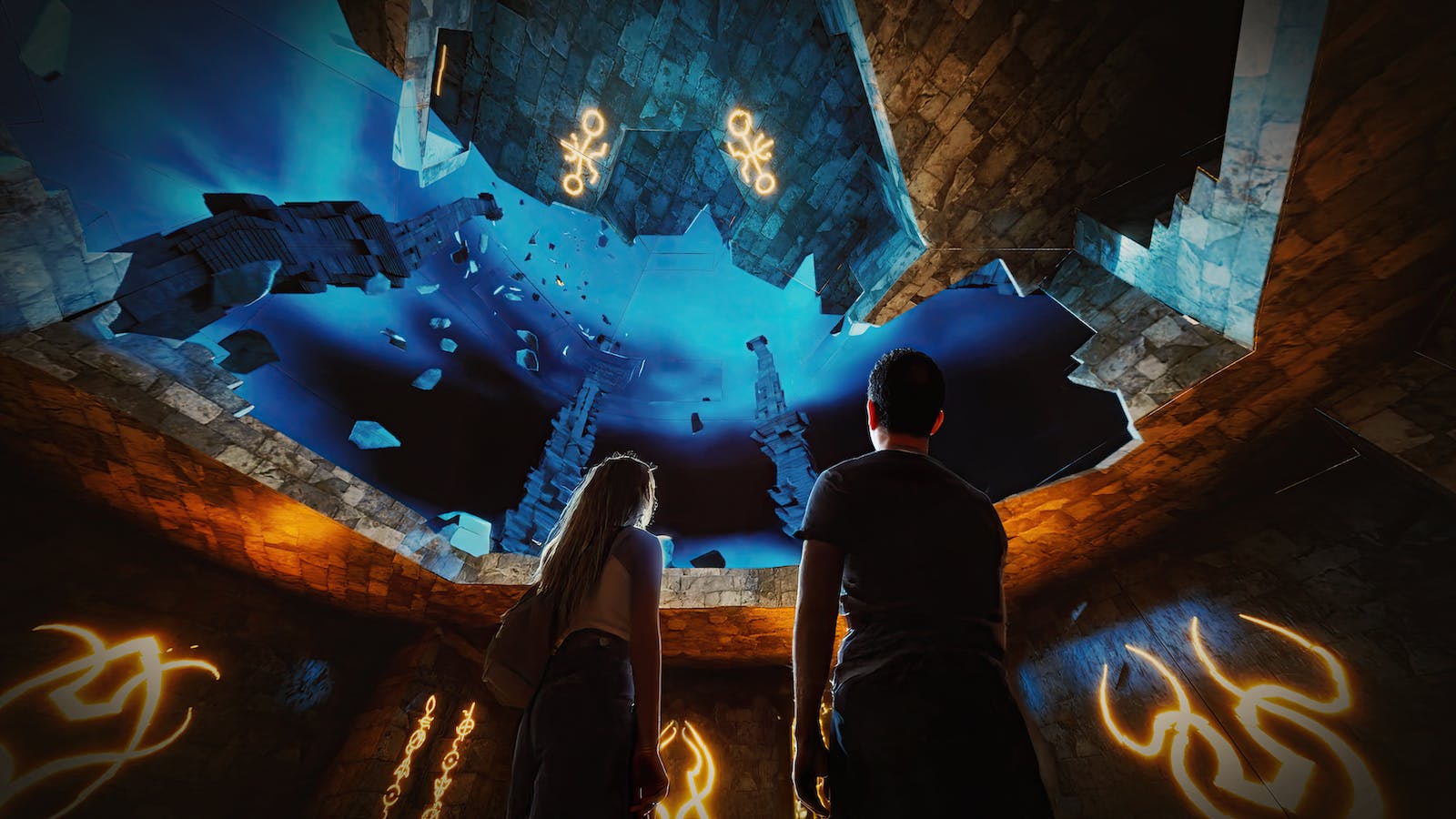 人们正在观看一个大型水族馆，里面有各种鱼类和水下结构。 地板有装饰图案。