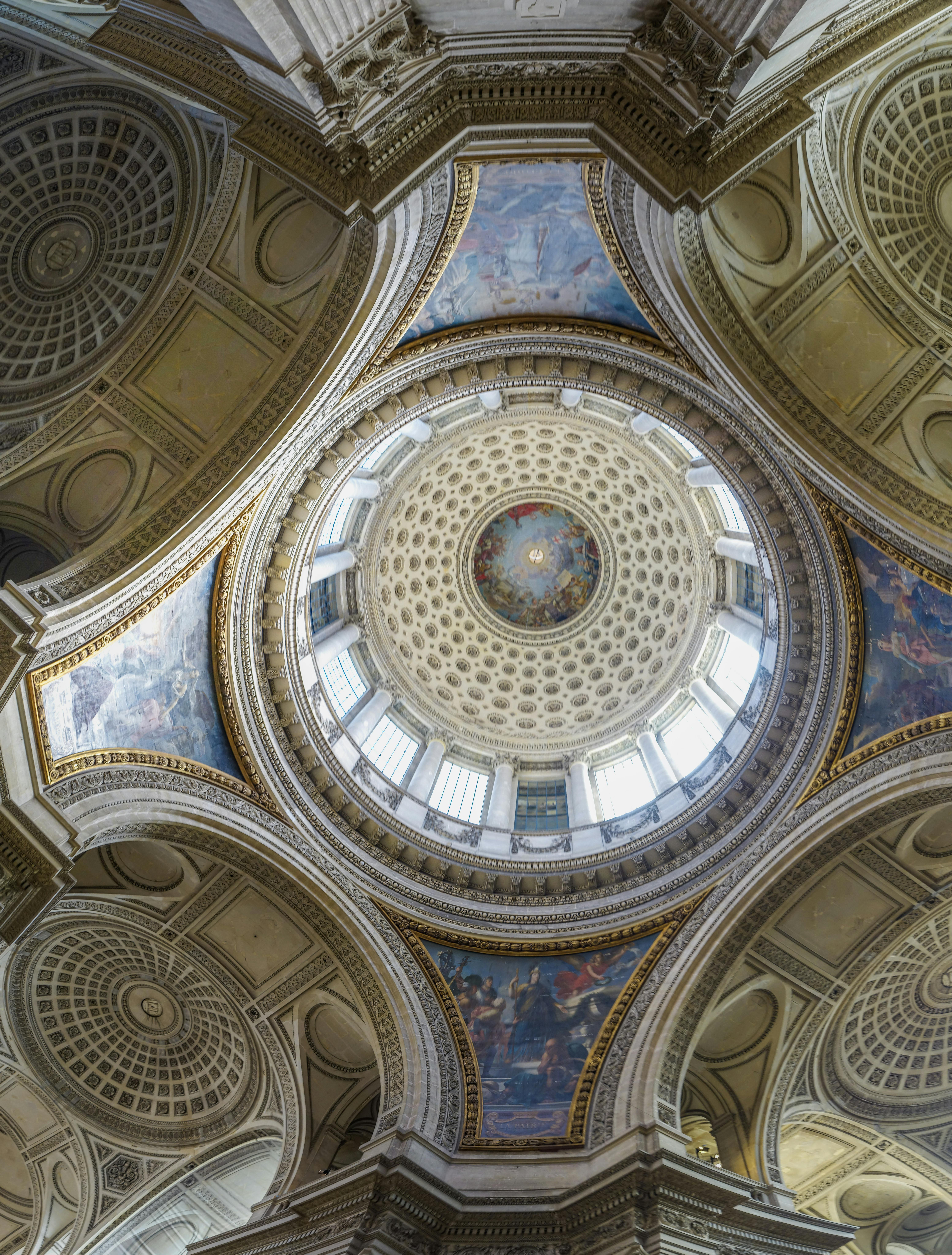 Ornate architectural ceiling with a central dome, intricate patterns, blue murals, and decorative arches.