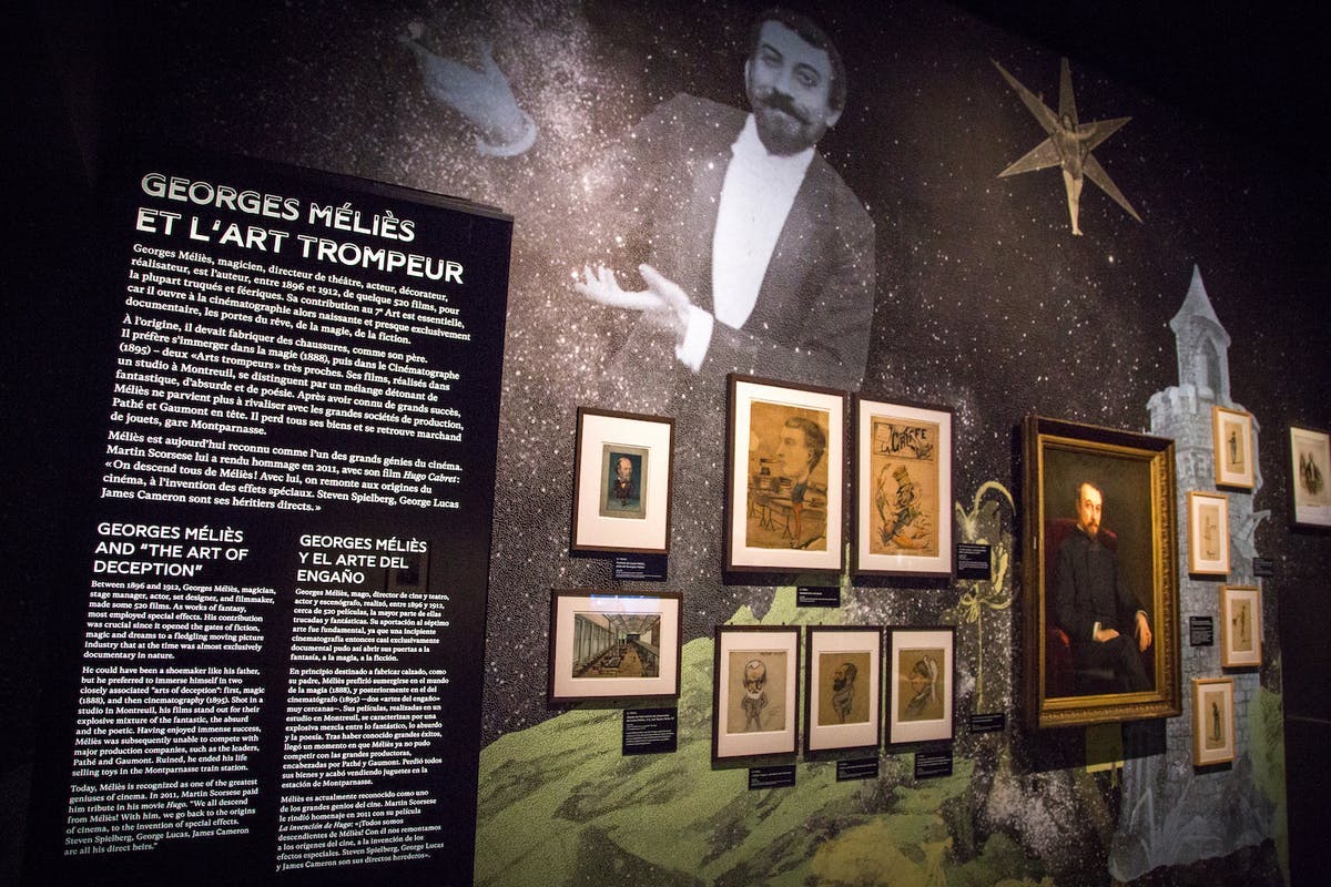 Ένα μουσειακό έκθεμα με ένα κολάζ εικόνων, πίνακες κειμένου και μια μεγάλη τοιχογραφία ενός άνδρα που χειρονομεί σε ένα έναστρο φόντο.