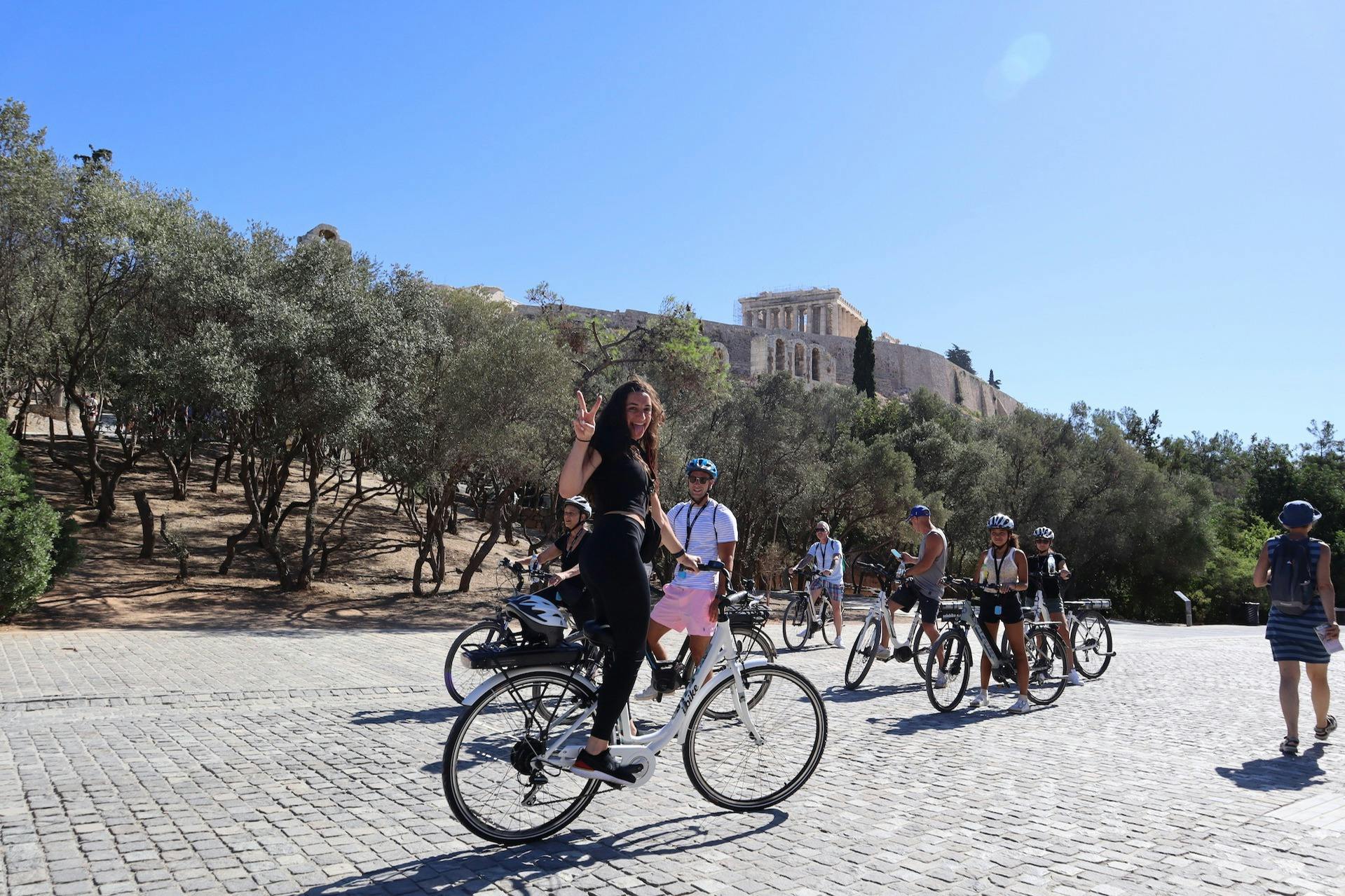 En gruppe passagerer og en entusiastisk pige står på en eBike under Akropolis-bakken.